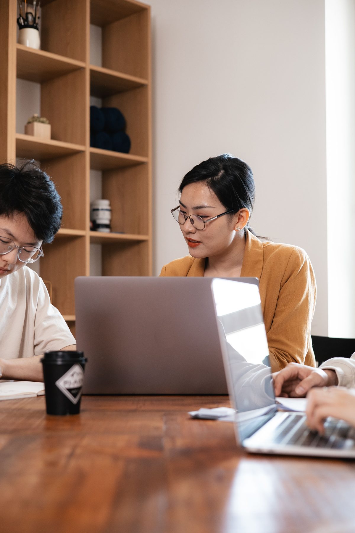 Colleagues working together at a shared table with laptops